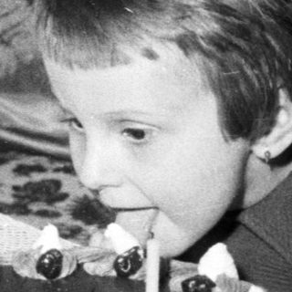 Child blows out candles on a cake indoors.