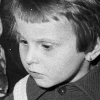 Here's a brief summary of the image: Child stares at a cake with lit candles.