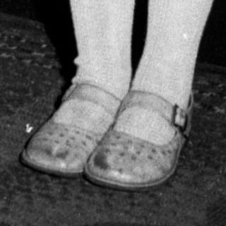 Black and white photo of a young girl in a dress.