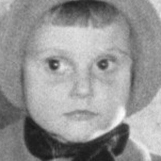Child in a coat and hat looks in a mirror.