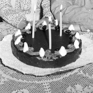 Two children with a birthday cake in a vintage setting.