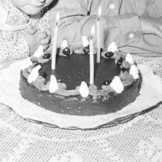 Two children sit near a cake with candles.