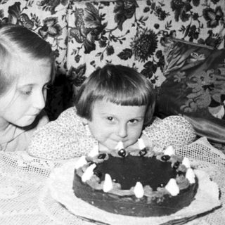 Two children blow out candles on a cake.