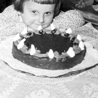 Two children blow out candles on a cake.