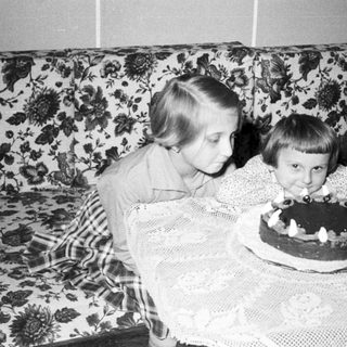 Two children blow out candles on a cake.