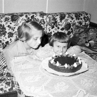 Two children blow out candles on a cake.