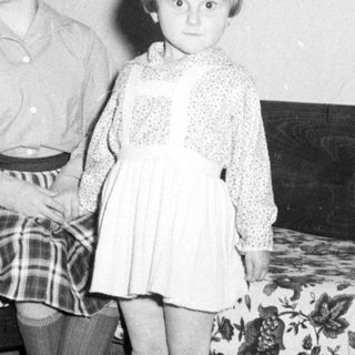 Two young girls sit beside a patterned couch.