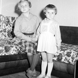 Two young girls sit beside a patterned couch.