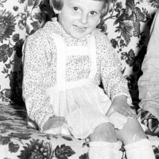 Two young girls sit on a floral couch.