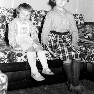 Two young girls sit on a floral couch.
