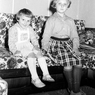 Two young girls sit on a floral couch.