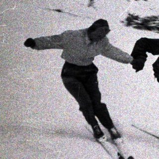 Two people are skiing down a snowy hillside.