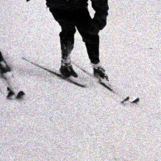 Two people are skiing down a snowy hillside.