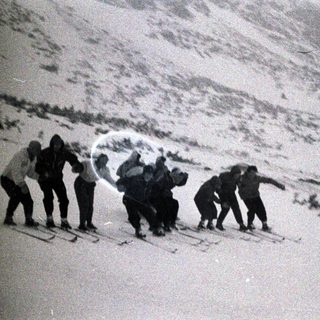 Here's a brief summary of the image: Group of people skiing down a snowy slope.