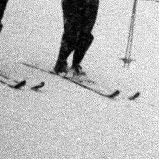 Three skiers descend a snow-covered slope in a mountain landscape.