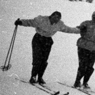 Three skiers descend a snow-covered slope in a mountain landscape.