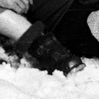 Injured man lies in snow, woman kneels nearby.