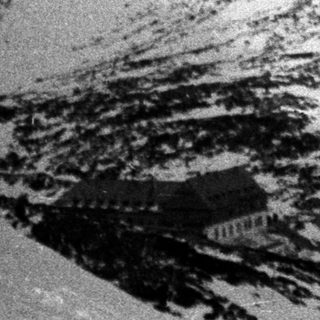 Black and white image showing a snowy mountain landscape.