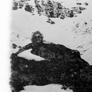 Man resting on rocks covered in snow.
