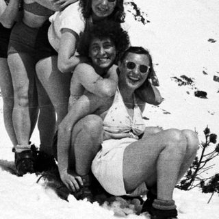 Group of people in swimwear pose on a snowy hillside.