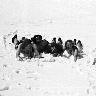 Three people lying playfully in the snow.