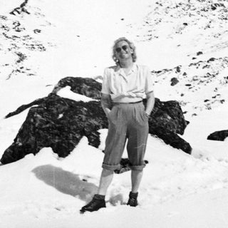 Woman stands in snow near a rocky outcropping.