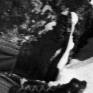 Woman in winter clothes lies in the snow, smiling.