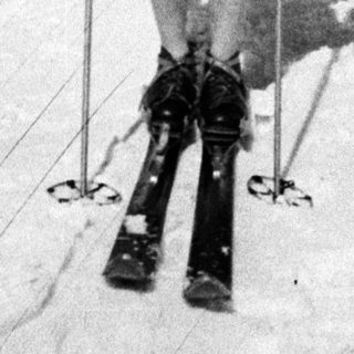 Here's a brief summary of the image: Woman in swimwear skis on a snowy slope.