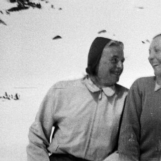 Two people smile in a snowy, outdoor setting.