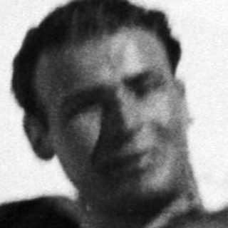 Man reclines in snow, wearing boots and shorts.