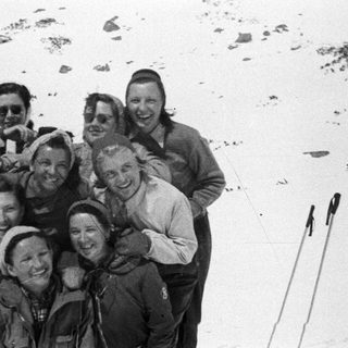 Group of people smiles for a photo in a snowy landscape.
