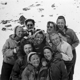 Group of people smiles for a photo in a snowy landscape.