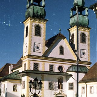 A church with twin towers stands under a bright sky.