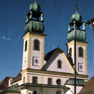 A church with twin towers stands under a bright sky.