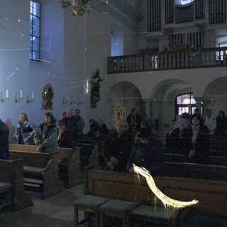 People inside a dimly lit, ornate church interior.