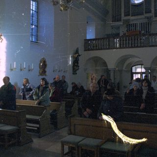 People inside a dimly lit, ornate church interior.