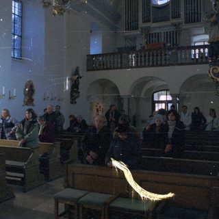 People inside a dimly lit, ornate church interior.