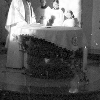 Here's a brief summary of the image: Priests performing a ceremony in a church setting.