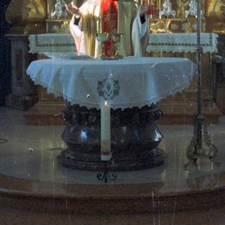 Here's a brief summary of the image: Priest officiating at an altar with attendants in a church.