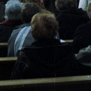People attend a service in an ornate church setting.