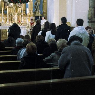People attend a service in an ornate church setting.