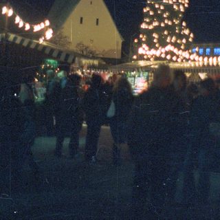 A brightly lit Christmas tree stands near a church.