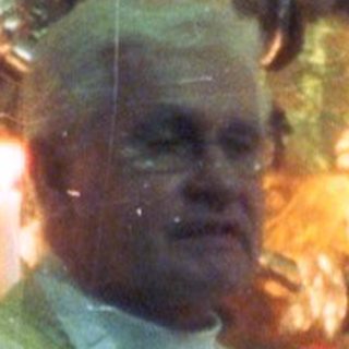 Priest in vestments stands before an ornate altar.