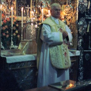 Priest in vestments stands before an ornate altar.