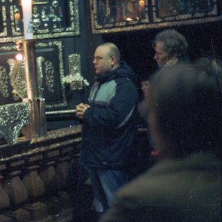Priest displays relic to onlookers in a richly decorated space.