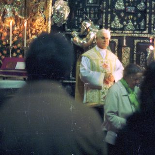 Priest performing a service with ornate religious backdrop.