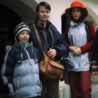 Four people stand outdoors, wearing warm clothing.