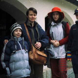 Four people stand outdoors, wearing warm clothing.