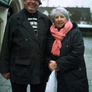 An older couple stands outside, bundled up against the cold.