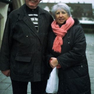 An older couple stands outside, bundled up against the cold.